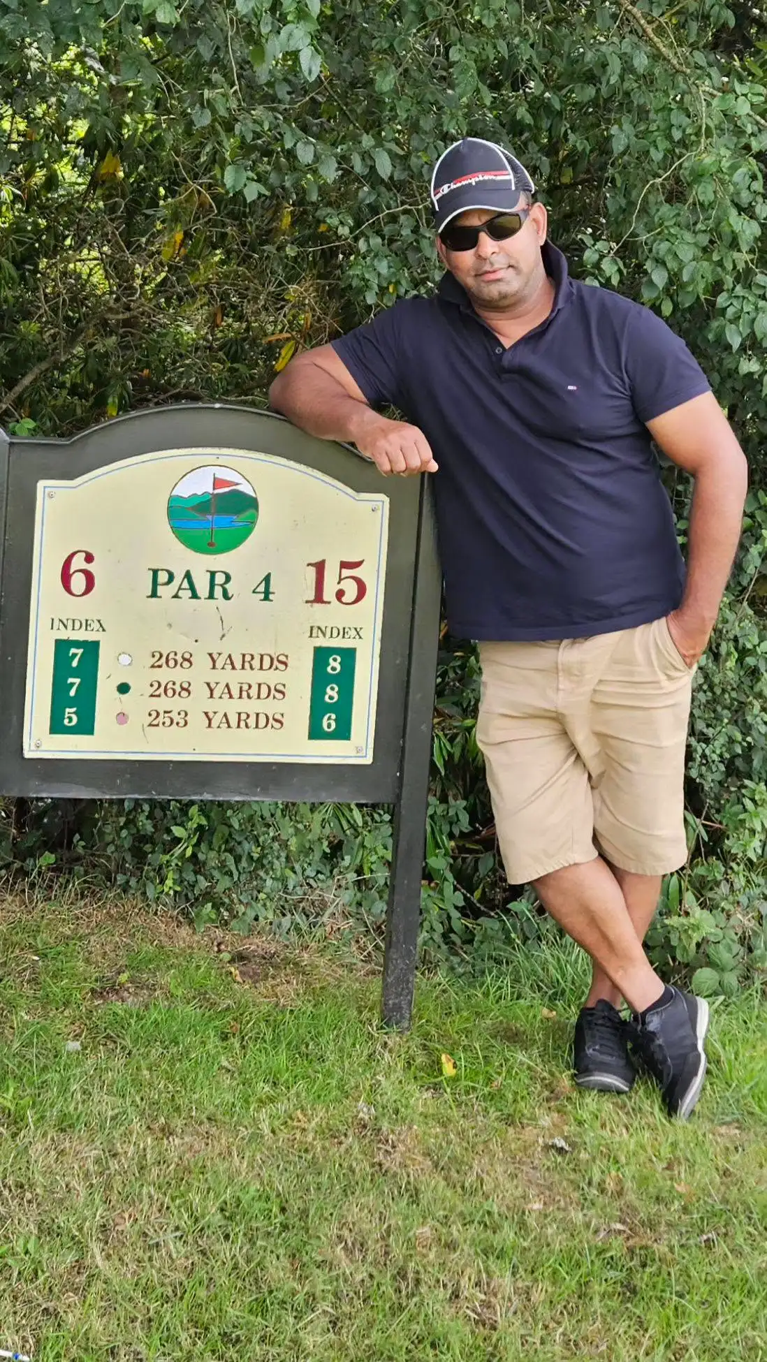 Minto Chowdhury leaning on the hole six sign at a golf course